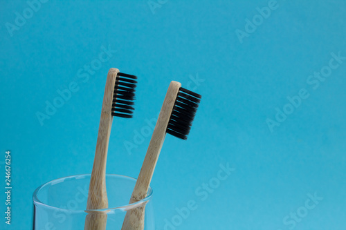 Two bamboo toothbrushes in the glass on the blue background.Copy space.Closeup.