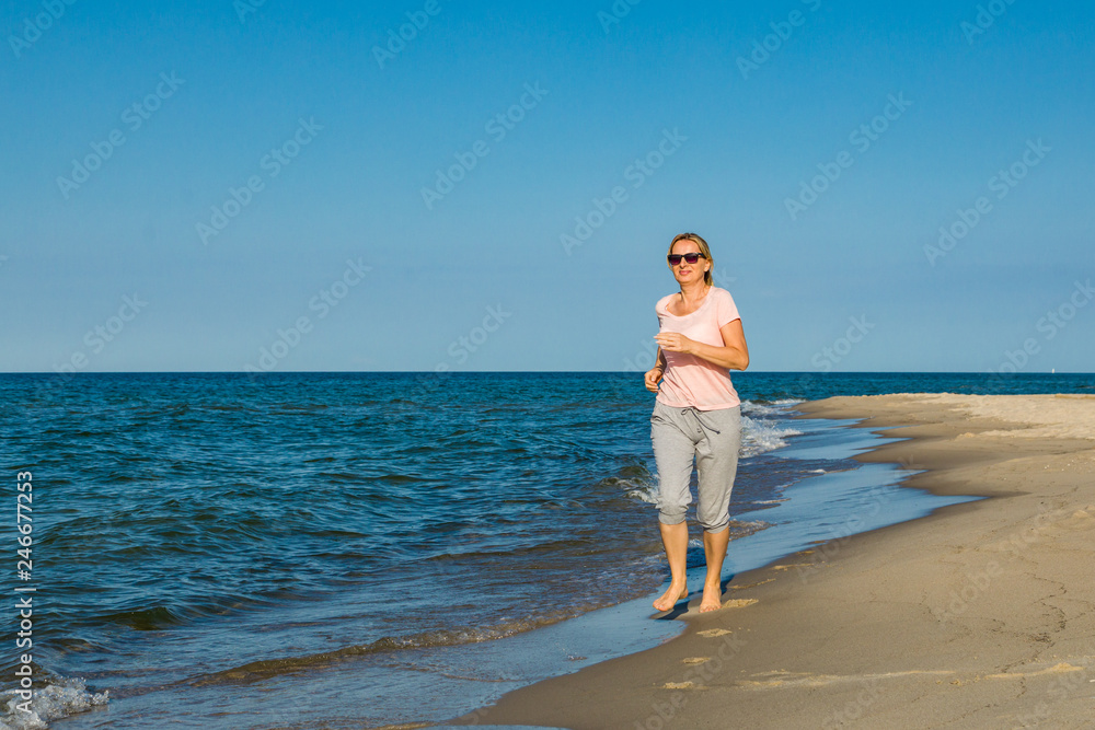 Middle-aged woman running on beach