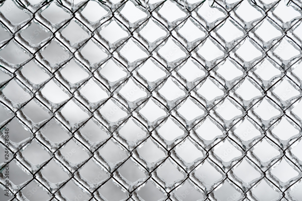 Fototapeta premium Background or pattern of frozen wire fence during winter, covered with snow and ice 