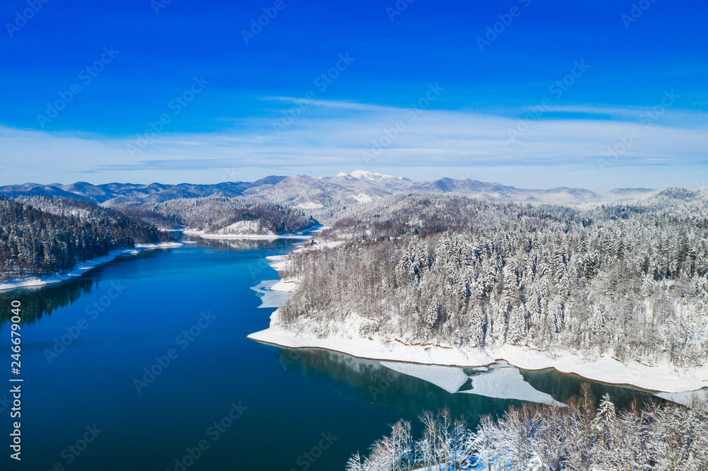 Obraz premium Croatian nature landscape in winter, panorama of Lokvarsko lake and woods under snow in Gorski kotar and Risnjak mountain in background from drone 