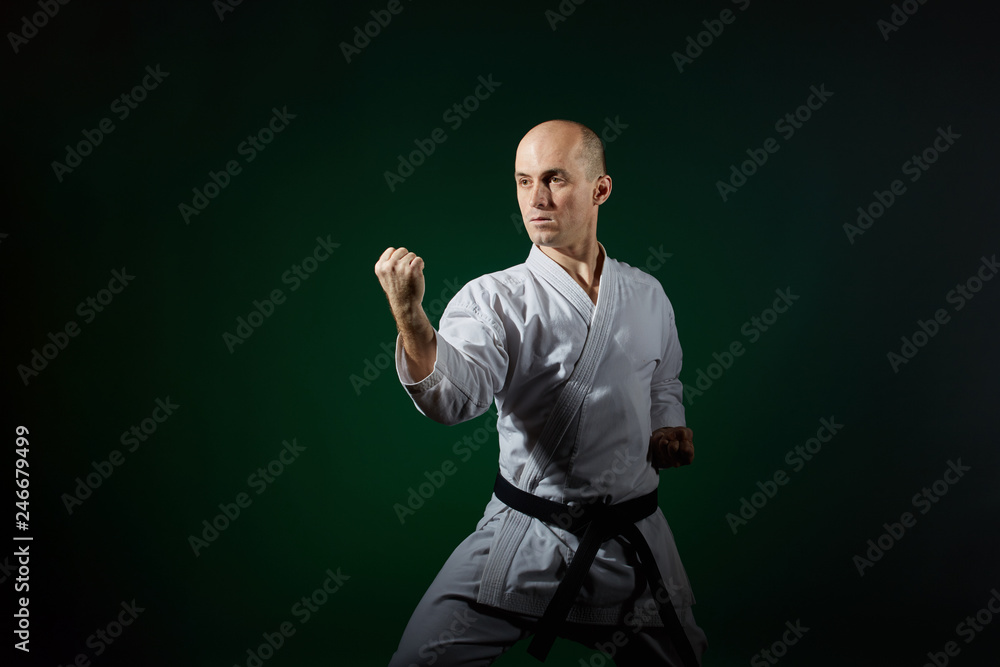 Athlete trains formal karate exercises on a dark green background