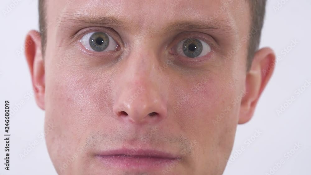 Close up face of mad man with gray eyes looking in camera with anger. Shooting on a white background. Close up face of mad man with gray eyes looking in camera with anger. Shooting on a white background.