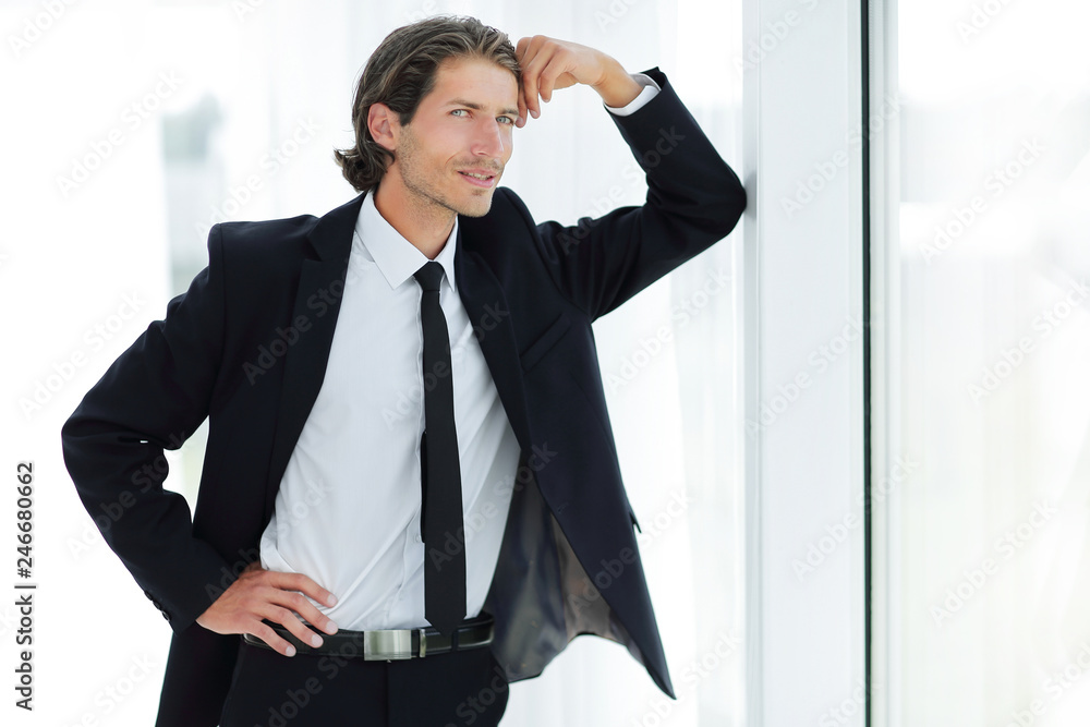 smiling businessman standing near window in office smiling businessman standing near window in office