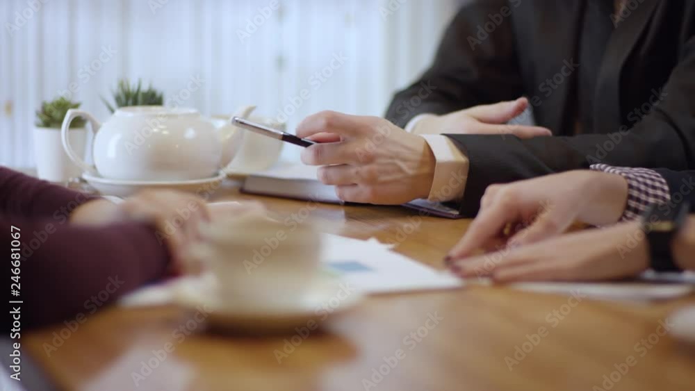 Three people are working together and discussing a contract in a cafe. The women and the man in a restaurant or a coffee shop are drinking coffee. It is a business meeting. They're hiring a new Three people are working together and discussing a contract in a cafe. The women and the man in a restaurant or a coffee shop are drinking coffee. It is a business meeting. They're hiring a new