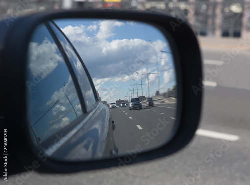 reflection in the rearview mirror of cars moving along the road