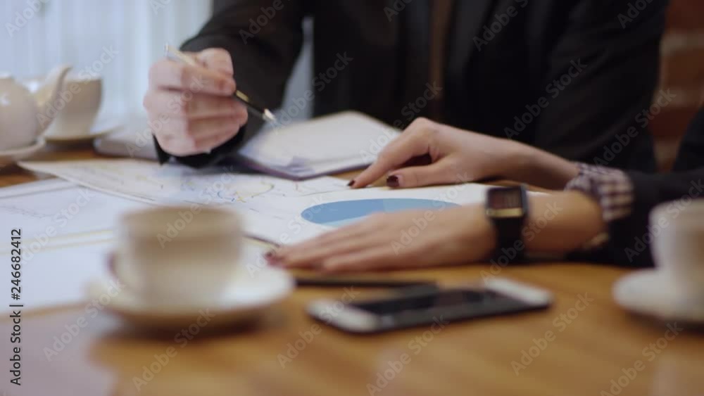 Two young people are working together and discussing projects in a cafe. The woman and the man in a restaurant or a coffee shop are drinking coffee. It is a business meeting. They are discussing the Two young people are working together and discussing projects in a cafe. The woman and the man in a restaurant or a coffee shop are drinking coffee. It is a business meeting. They are discussing the