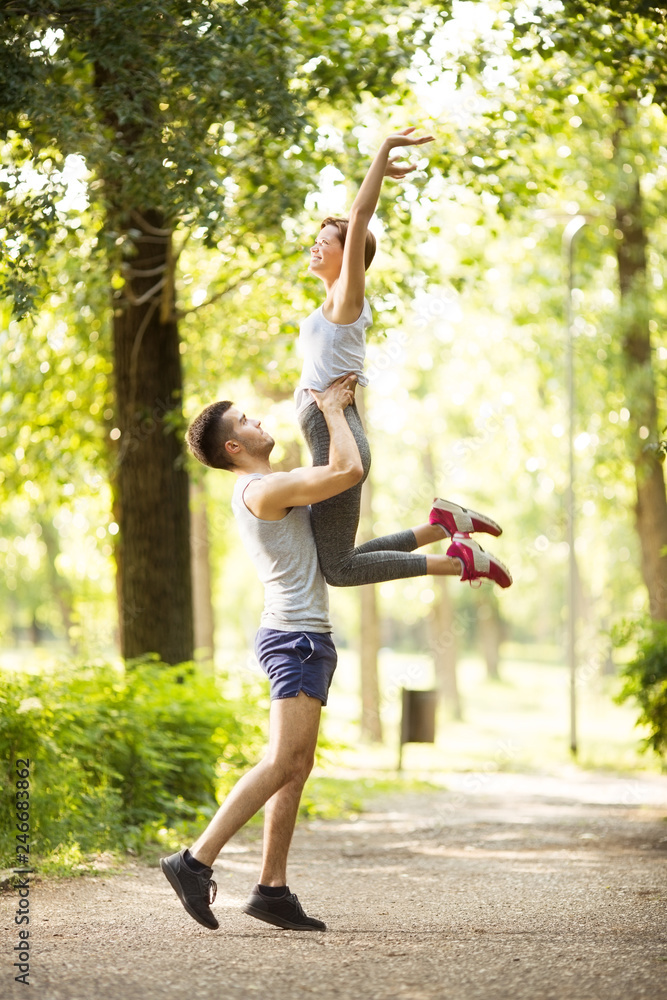 Young happy couple doing stretching exercises in park