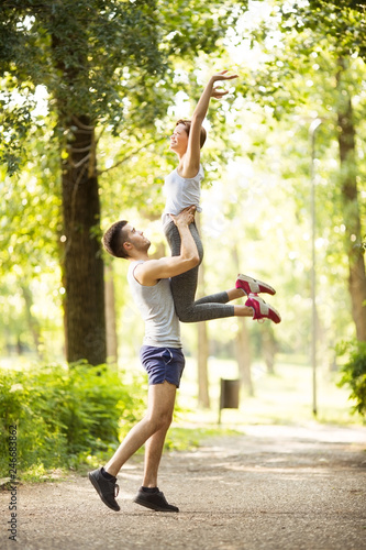 Young happy couple doing stretching exercises in park