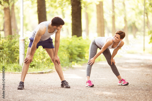 Young beautiful couple stretching in park