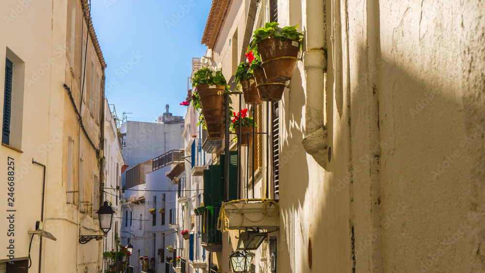 Fototapeta premium small town in Barcelona with traditional houses and flowers in the balcony and a pedestrian street at Sitges