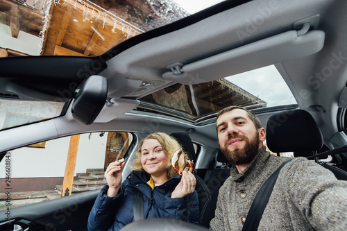 Young couple taking selfie in a car with glass roof