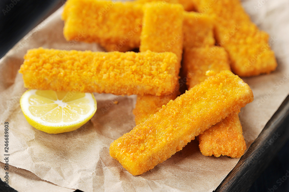 fried breaded fish sticks and lemon on paper fried breaded fish sticks and lemon on paper