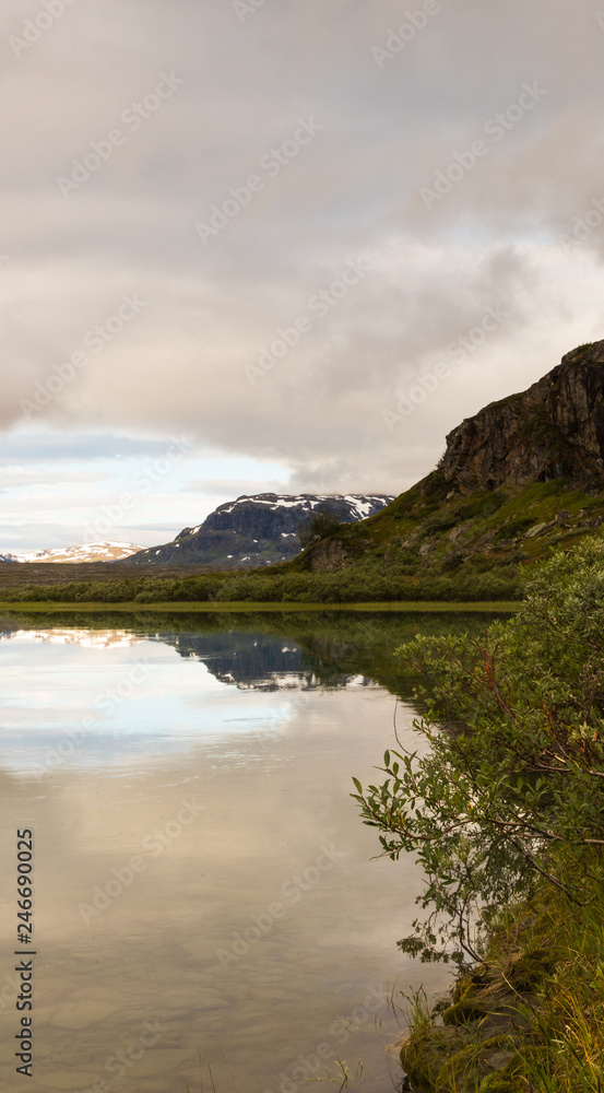 Mountain reflecting in the water in the lake at Alesjaure mountain cabin along the hike of Kungsleden (Kings trail) in northern Sweden. Shot during sunrise an early morning in summer. 