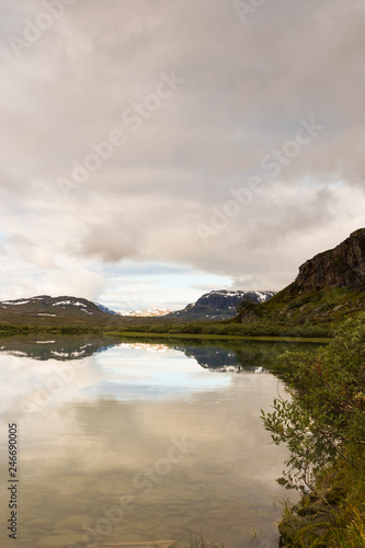 Mountain reflecting in the water in the lake at Alesjaure mountain cabin along the hike of Kungsleden (Kings trail) in northern Sweden. Shot during sunrise an early morning in summer. 