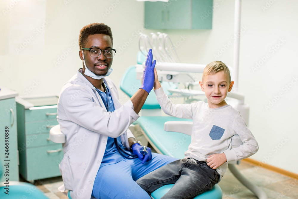 Happy little boy giving high five after health exam at African American doctor's office Happy little boy giving high five after health exam at African American doctor's office