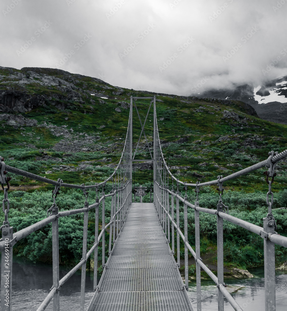 Bridge leading over the lake at Alesjaure mountain station an early morning before sunrise during the hike of Kungsleden (Kings trail) in northern Sweden. 
