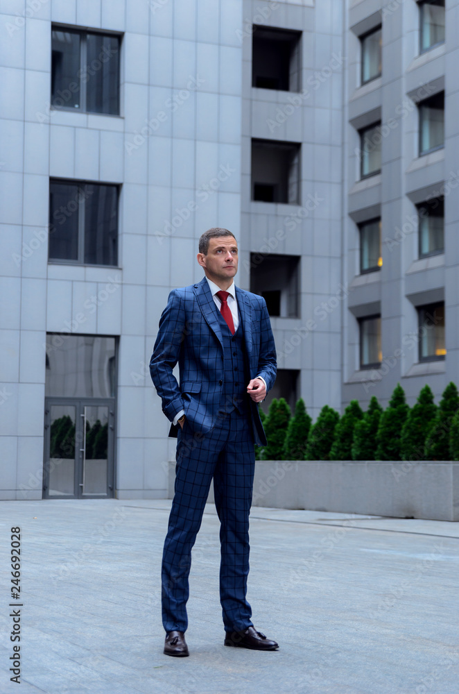 Charismatic man in a plaid suit on the background of the business center (office). Business portrait of a stylish, fashionable employee (manager). Charismatic man in a plaid suit on the background of the business center (office). Business portrait of a stylish, fashionable employee (manager).