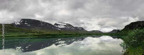 Panorama of Alesjaure lake with mountains behind creating refletioctions just before sunrise. Captured while walking Kungsleden (Kings path) in northern Sweden. Just outside Alesjaure cabin.