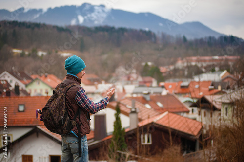 A man on the background of roofs and mountains on a cloudy day.