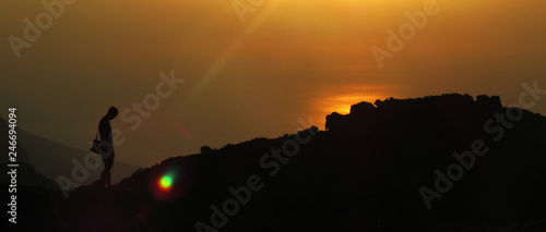 Fototapeta Naklejka Na Ścianę i Meble -  Person´s silhouette on a hill in front of a sunset over the ocean on Table Mount, Cape Town, South Africa.