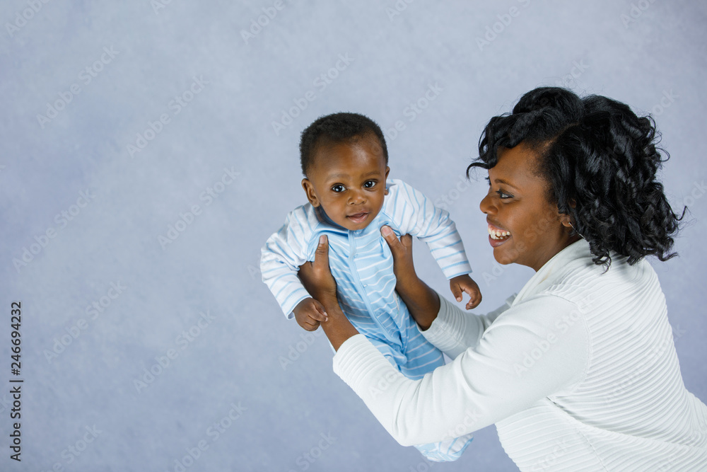 Beautiful African Amercian Woman wHolding Her Baby boy on a Gray Background Beautiful African Amercian Woman wHolding Her Baby boy on a Gray Background