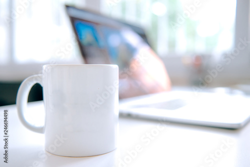 cup of coffee and laptop on the table. Coffee  mug and notebook on the table in office working interior.
