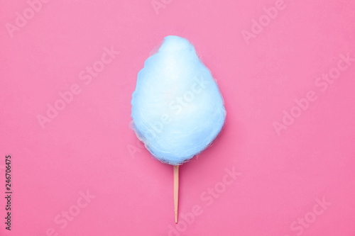 Stick with blue yummy cotton candy on pink background, top view