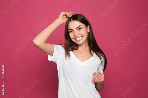 Portrait of young woman laughing on color background