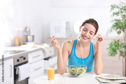 Young woman in fitness clothes having healthy breakfast at home. Space for text