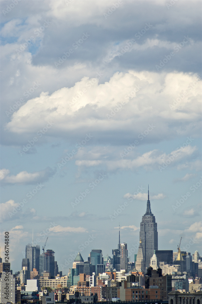 Obraz premium A sweeping view of New York City's midtown Manhattan with some of its iconic buildings, skyscrapers and structures, from the vantage point of Brooklyn Bridge.