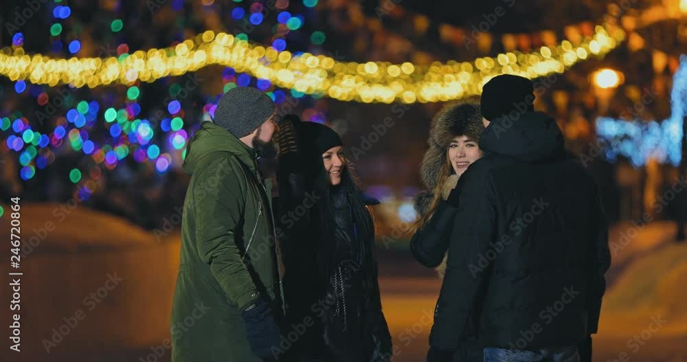 Company stands on the street in winter. Guy with the beard tells his friends, and they laugh. Side span of the camera. Company stands on the street in winter. Guy with the beard tells his friends, and they laugh. Side span of the camera.