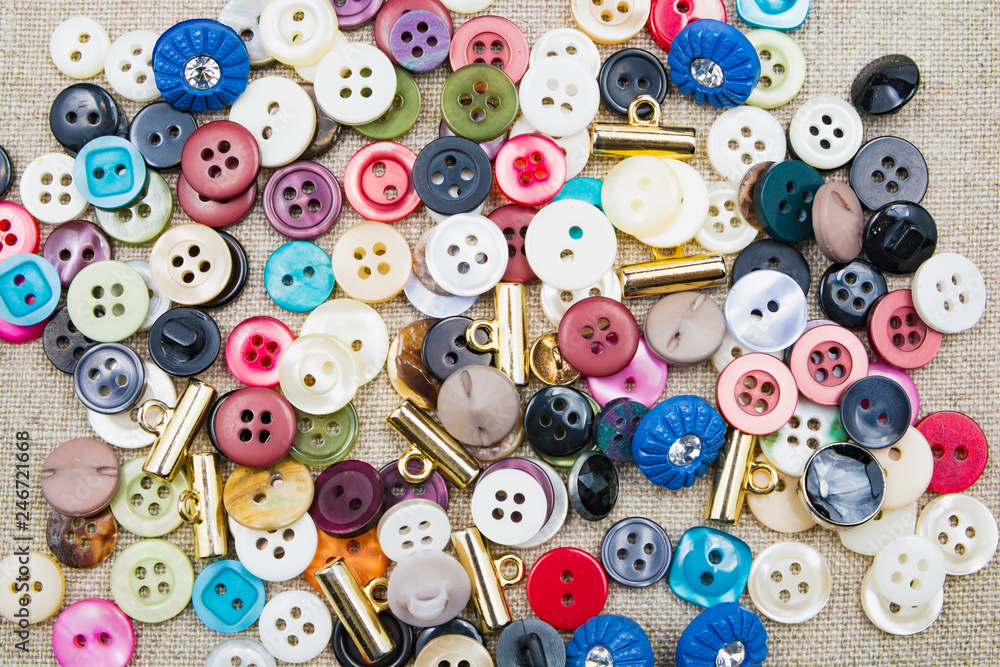 Lots of colorful sewn-on buttons of different colors on a linen lightweight natural fabrics Lots of colorful sewn-on buttons of different colors on a linen lightweight natural fabrics