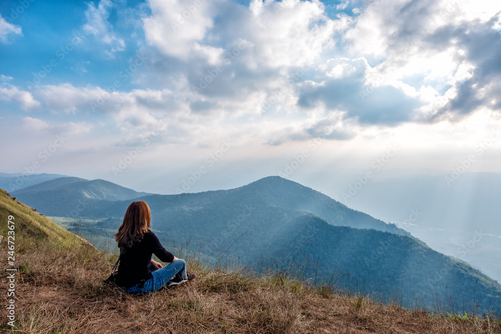 A woman sitting and watching sunset with mountains view in the evening