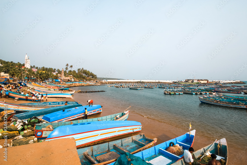 Vizhinjam fishing habour with colorful fishing boats in the foreground. Vizhinjam International Seaport is a proposed port by the Arabian Sea at Thiruvananthapuram in India. 