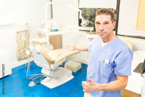 Professional male dentist smiling at camera in office