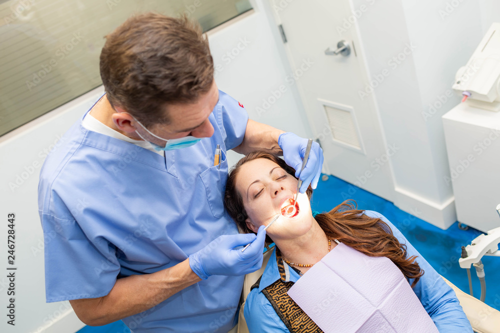 Dentist performing teeth treatment with female patient open mouth Dentist performing teeth treatment with female patient open mouth