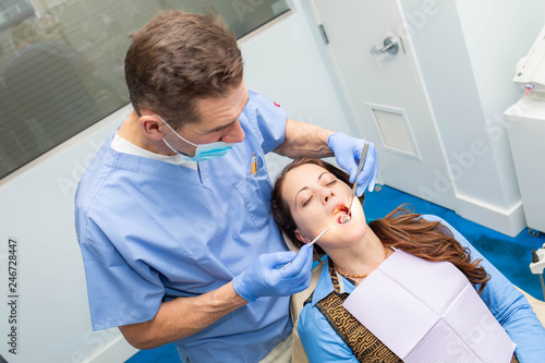 Dentist performing teeth treatment with female patient open mouth