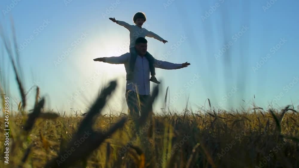 silhouette of father and son playing, airplane arms raised together at sunset in wheat field, happy family walking outdoors. child boy having fun, rising up hands, travel, holiday flight nature summer silhouette of father and son playing, airplane arms raised together at sunset in wheat field, happy family walking outdoors. child boy having fun, rising up hands, travel, holiday flight nature summer