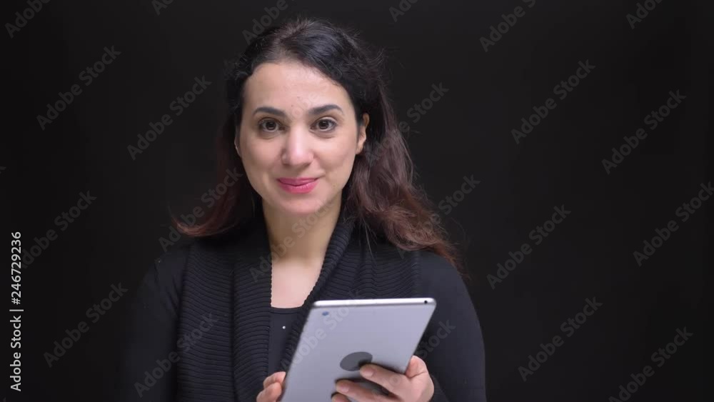 Closeup portrait of young attractive caucasian female using tablet then looking at camera and smiling Closeup portrait of young attractive caucasian female using tablet then looking at camera and smiling