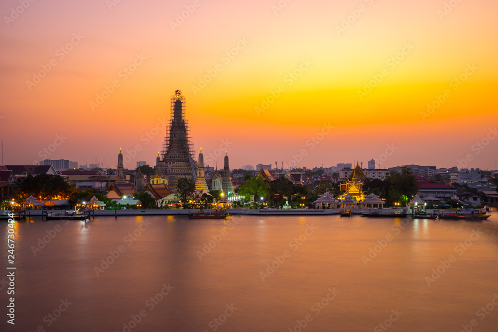 Wat Arun Temple Beside Chao Phraya River at Twilight Time in Bangkok, Thailand. One of the Most Famous Place of Thailand's Landmarks. Beautiful Sunset Sky with Smooth Water.