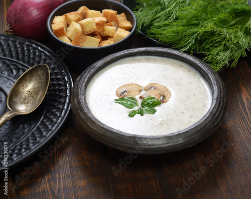 Champignon mushroom cream soup in bowl on wooden background. Rustic style. 