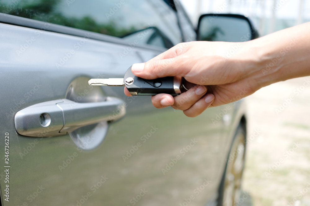 woman's hand holds a car key. She is about to open the car door with keys to drive and travel.