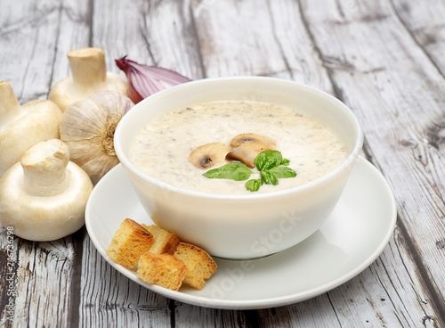 Champignon mushroom cream soup in bowl on wooden background. Rustic style. 