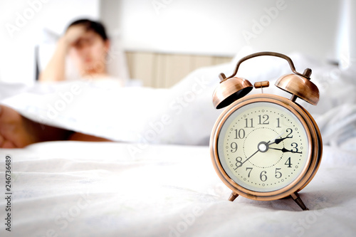 alarm clock young man unhappy has an headache . sleep insomnia night time on bed in his room Health care concept.