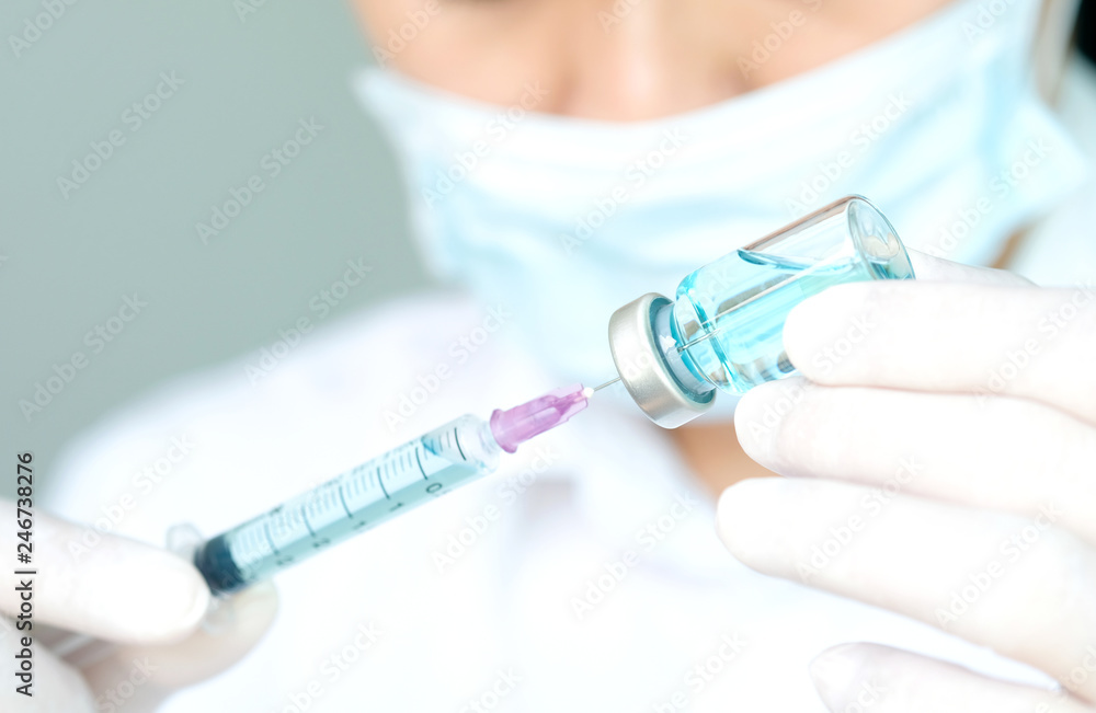 doctor's hand holds a syringe and a blue vaccine bottle at the hospital. Health and medical concepts doctor's hand holds a syringe and a blue vaccine bottle at the hospital. Health and medical concepts