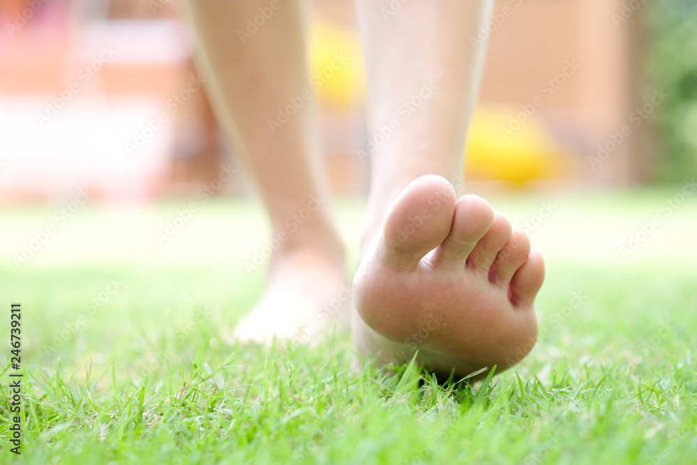Naklejka premium Leg of woman is on the ground. She is about to walk down the grass to exercise in the morning. Health and Relaxation Concepts