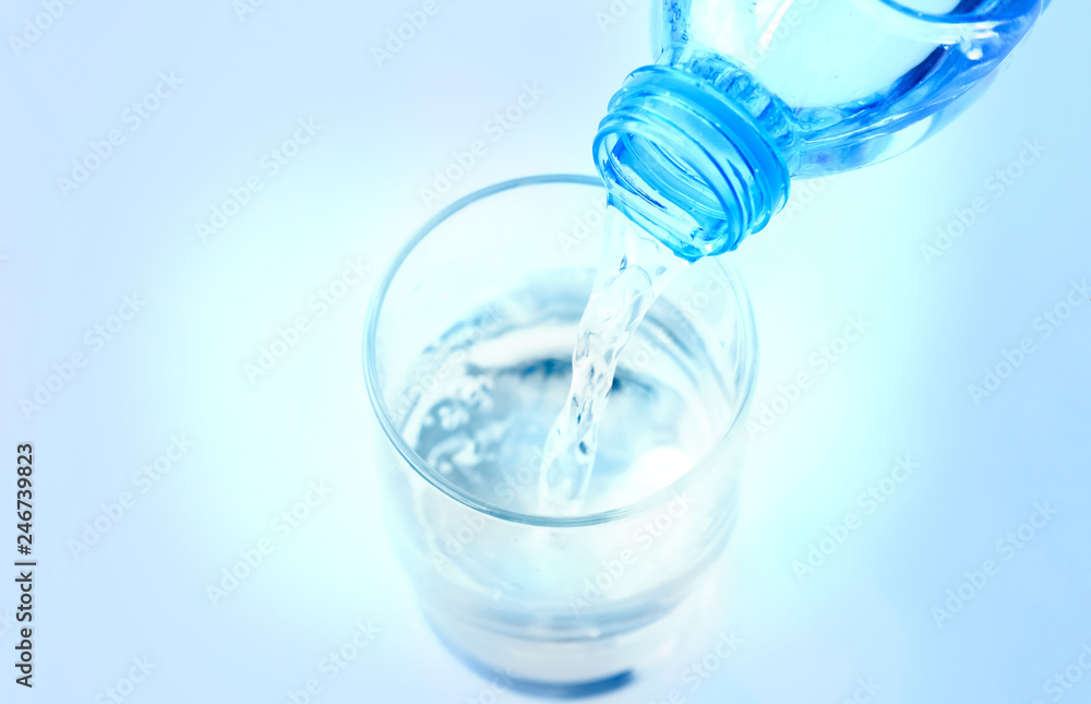 Pour pure water from a bottle of mineral water into a glass. Pour pure water from a bottle of mineral water into a glass.