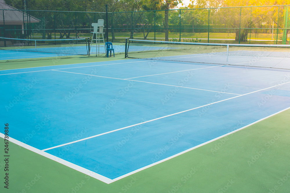 Empty outdoor blue tennis hard court in public park. (Selective focus)