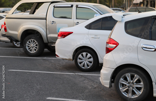 Closeup of back or rear side of white car and other cars parking in parking area in the evening of sunny day.  © Amphon