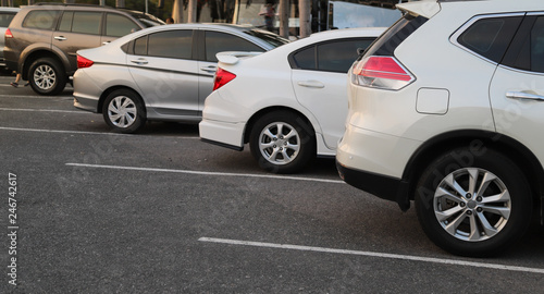 Closeup of back or rear side of white car and other cars parking in parking area in the evening of sunny day. 